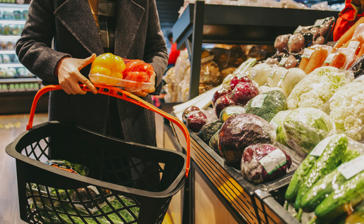 Woman holding a shopping basket holding a vegetable