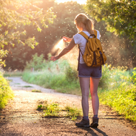 Woman applying mosquito repellent on a hiking trail