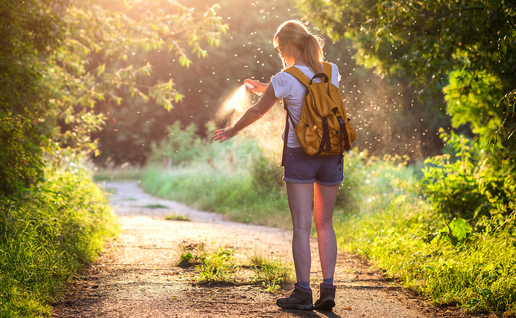 Woman applying mosquito repellent on a hiking trail