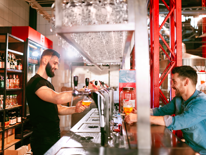 A man in a bar serving a beer