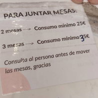 Sign at a Spain café terrace stating customers must meet a minimum spend to join tables together