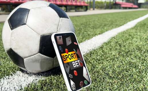 Live in-play betting app on a mobile phone screen on a football pitch with a football