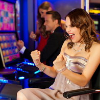Young woman sat at slot machines in casino and cheering as has won