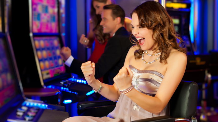 Young woman sat at slot machines in casino and cheering as has won