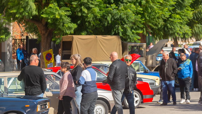 People inspecting used vehicles at a public car auction in Spain with several cars parked outdoors
