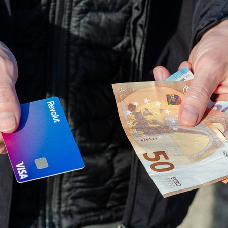 Person holding euro cash and a bank card, illustrating payment options in Spain shops