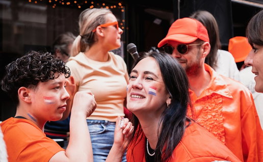 People dressed in orange with flags celebrating Dutch Kings Day