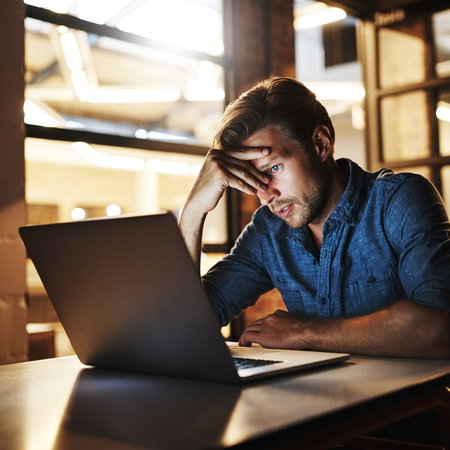 Man looking worried at laptop after receiving suspicious scam email in Spain