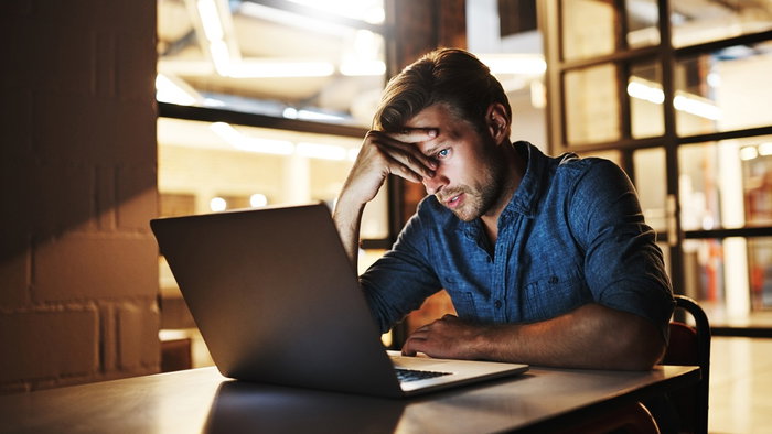 Man looking worried at laptop after receiving suspicious scam email in Spain