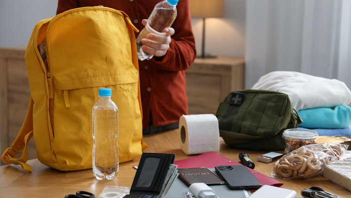 Person preparing an emergency kit with water, documents, power bank and supplies at home in Belgium
