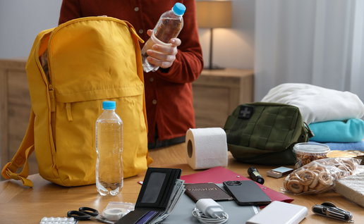 Person preparing an emergency kit with water, documents, power bank and supplies at home in Belgium
