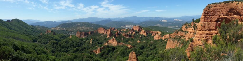 Panoramic view of Las Médulas in León, Spain, with red rock formations and green hills