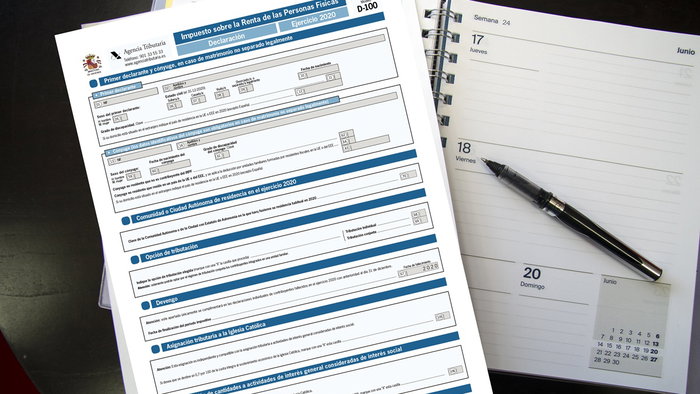 Spanish income tax form (Declaración de la Renta) next to an open planner and pen