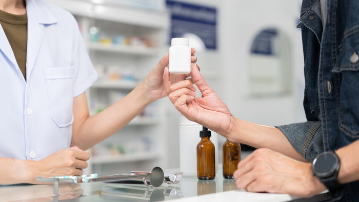 Person purchasing homeopathic remedies at a pharmacy counter in Spain