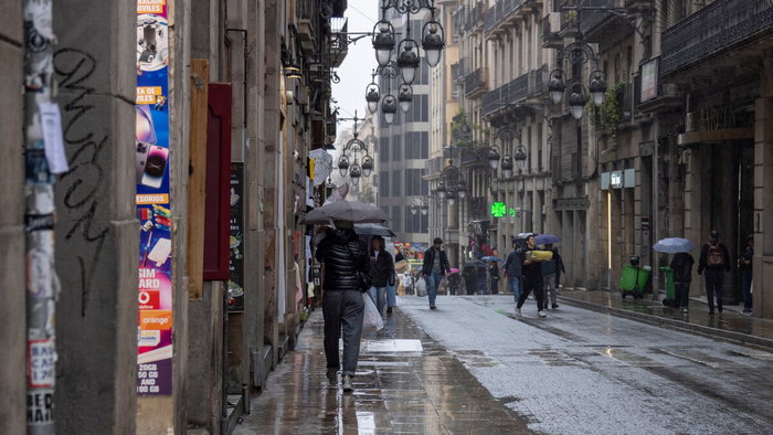 Rainstorm flooding city street in Spain with cars driving through water during severe weather