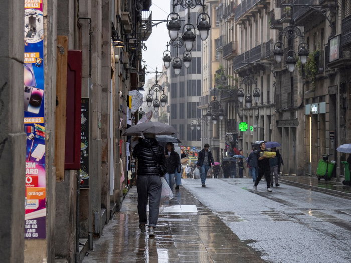 Rainstorm flooding city street in Spain with cars driving through water during severe weather