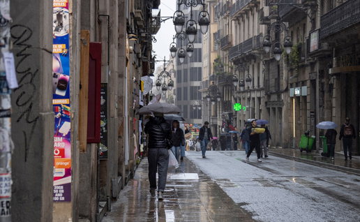 Rainstorm flooding city street in Spain with cars driving through water during severe weather