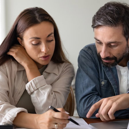 People reviewing mortgage documents with calculator amid changing interest rate expectations in Spain