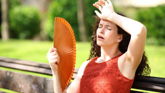 Woman in a park suffering heat stroke fanning