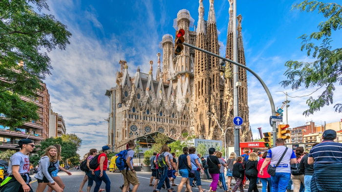 Tourists crossing the street to go to visit the Sagrada Familia basilica church