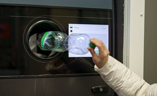 Woman placing a plastic bottle inside a recycling machine