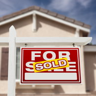 House with “For Sale” sign marked “Sold” in front of a residential property
