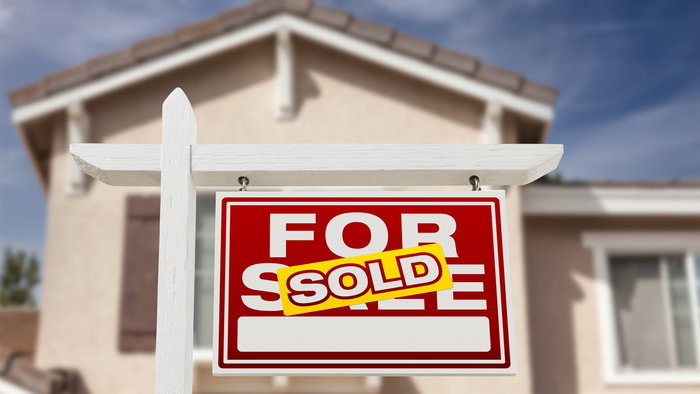 House with “For Sale” sign marked “Sold” in front of a residential property