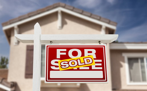 House with “For Sale” sign marked “Sold” in front of a residential property