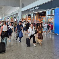Passengers walk through a busy airport terminal as airlines warn of possible summer flight disruptions linked to fuel supply concerns.