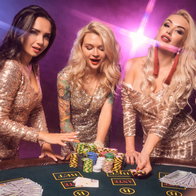 3 beautiful girs with perfect hairstyles & make up at a casino table stood by a pile of casino chips