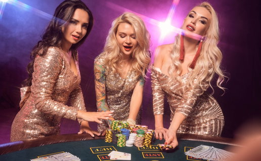 3 beautiful girs with perfect hairstyles & make up at a casino table stood by a pile of casino chips
