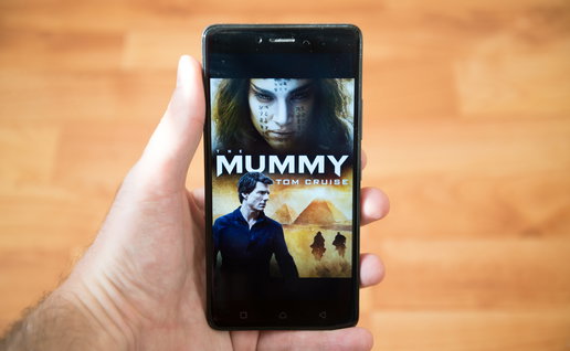 Person holding a mobile phone with the poster for the movie the Mummy from 2017