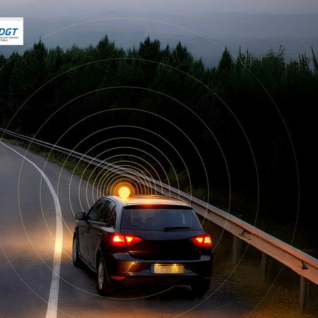 Official DGT image showing a car stopped on a road at night using a connected V16 emergency warning light in Spain.