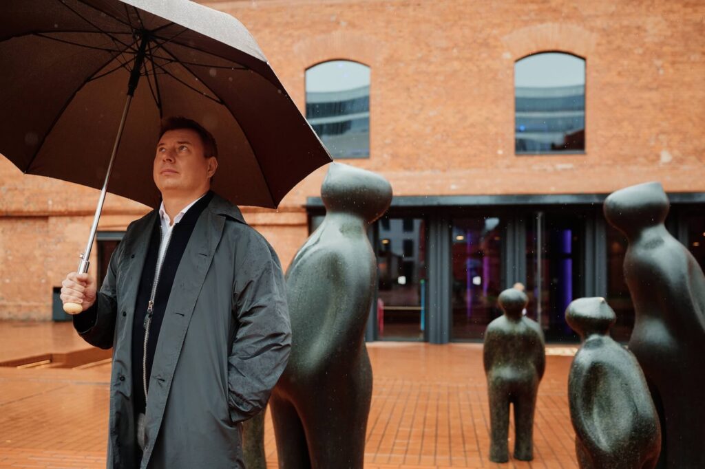 Denis Kitaev beside Guido Deleu’s The Visitor sculptures at Lucky