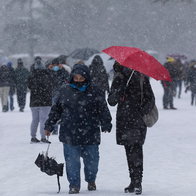People walk through heavy snowfall as forecasters warn of colder weather and possible snow returning to Spain in May.