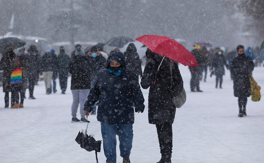 People walk through heavy snowfall as forecasters warn of colder weather and possible snow returning to Spain in May.