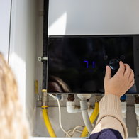 Homeowner adjusting a gas boiler as EU plans phase out of gas heating systems