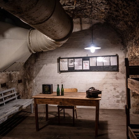 Interior of an underground bunker in Germany with wooden benches, bunk beds and ventilation pipes as Europe discusses civil defence preparedness.