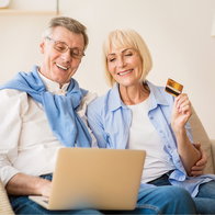 Excited older couple on a laptop sorting our their tax return