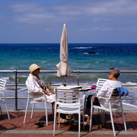 Two elderly women sitting at a table by the sea
