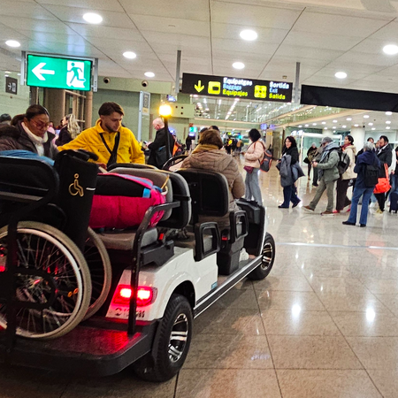 Mobility assistance buggy carrying two elderly passengers with a wheelchair
