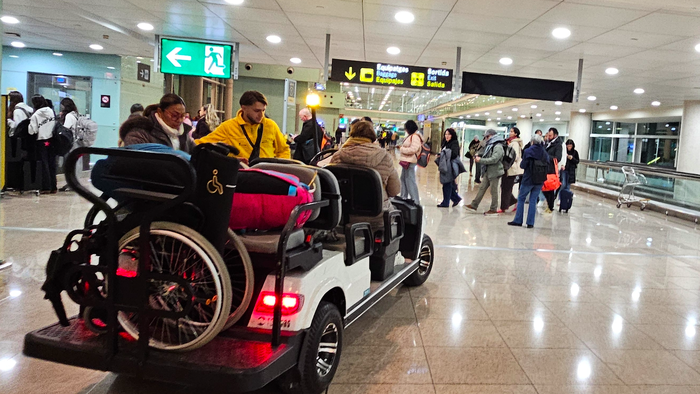 Mobility assistance buggy carrying two elderly passengers with a wheelchair
