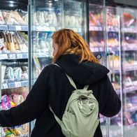 Woman getting food from the refrigerated section of a supermarket