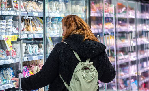 Woman getting food from the refrigerated section of a supermarket