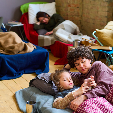 An overcrowded bedroom with 4 people sleeping in make shift beds