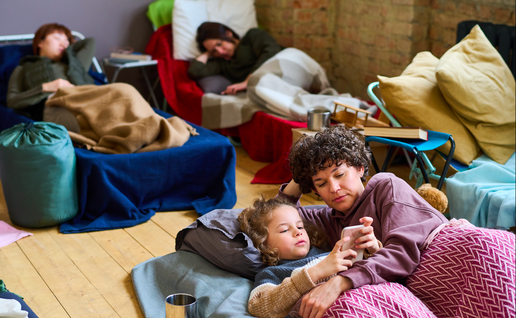 An overcrowded bedroom with 4 people sleeping in make shift beds