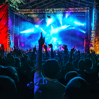 A crowd of people in front of a stage at a night concert