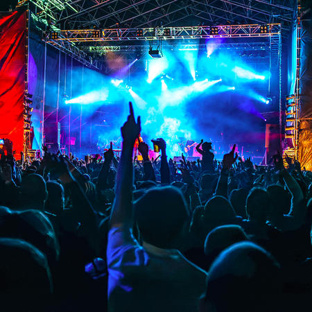 A crowd of people in front of a stage at a night concert