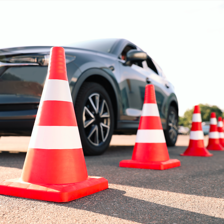Traffic cones on the side of the road with cars passing by