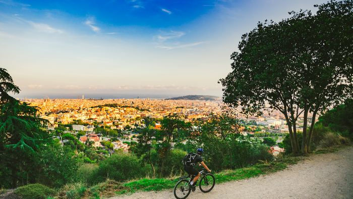 Man cycling on a country road with Barcelona in the background
